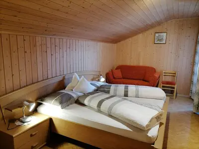 a bedroom with a bed and a red chair at Gasthaus Oberkirn in Schenna