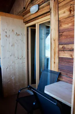 a room with a bed and a chair in a cabin at Gasthaus Oberkirn in Schenna