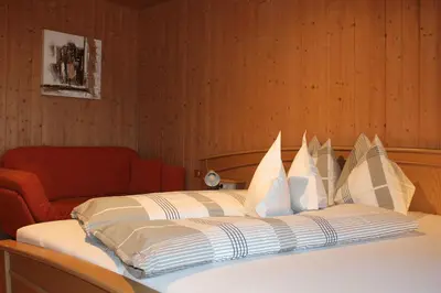 a bed with white pillows and a red chair at Gasthaus Oberkirn in Schenna