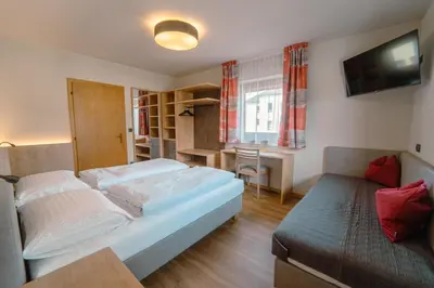 a bedroom with a bed and a desk and a television at Gasthof Paul in Naz-Sciaves