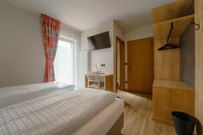 a bedroom with a bed and a desk and a window at Gasthof Paul in Naz-Sciaves