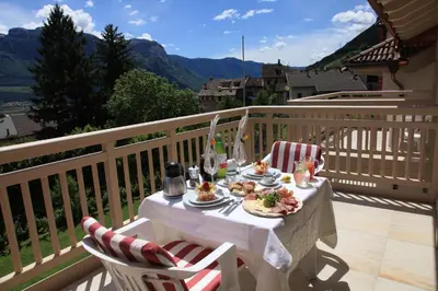 a table with plates of food on a balcony at Überbacherhof in Termeno