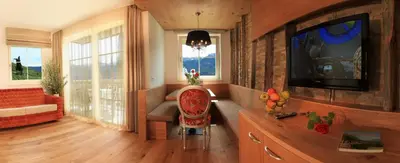 a living room with a flat screen tv and a chair at Überbacherhof in Termeno