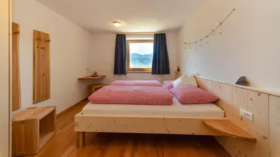 a bedroom with a bed with pink sheets and a window at Gruberhof a quiet place Gereuth Brixen in Bressanone