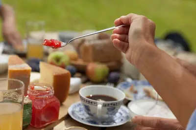 a person holding a spoon with food on a table at Apartments Schmalzerhof - Eppan an der Weinstraße in Appiano Sulla Strada Del Vino