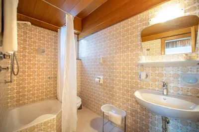 a bathroom with a sink and a tub and a toilet at Garni Bondi in Selva di Val Gardena
