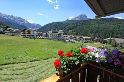 a balcony with red and purple flowers on a mountain at Garni Bondi in Selva di Val Gardena