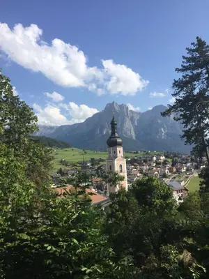 a town with a clock tower with mountains in the background at Garni Waldfrieden in Castelrotto