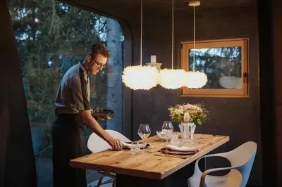 a man standing at a wooden table with wine glasses at Mi Chalet in La Villa