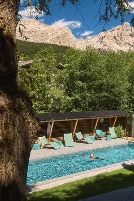 a person in a swimming pool with chairs and a building at Mi Chalet in La Villa