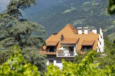 a house with an orange roof on a mountain at Ladurnerhof Boutique Apartments Meran in Merano