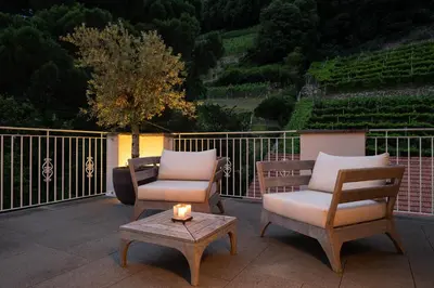 a patio with two chairs and a table with a candle at Ladurnerhof Boutique Apartments Meran in Merano