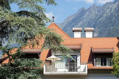 a house with an orange roof and a balcony with an umbrella at Ladurnerhof Boutique Apartments Meran in Merano
