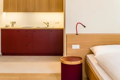 a bedroom with red cabinets and a bed and a sink at Ladurnerhof Boutique Apartments Meran in Merano