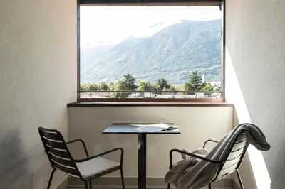a table and chairs in a room with a large window at Ladurnerhof Boutique Apartments Meran in Merano