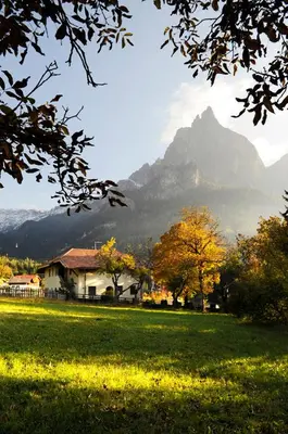 a house in a field with a mountain in the background at Villa Tilia in Siusi