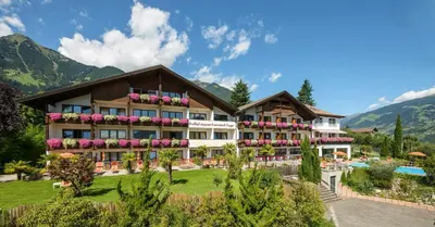 a hotel with a pool and mountains in the background at Hotel Appartement Inge in Tirolo