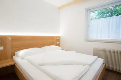 a bedroom with a bed with white sheets and a window at Hotel Appartement Inge in Tirolo