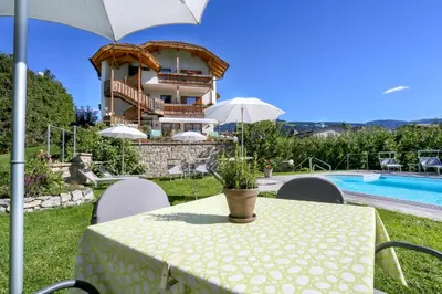 a table with an umbrella in front of a house at Hotel Ploseblick in Naz-Sciaves