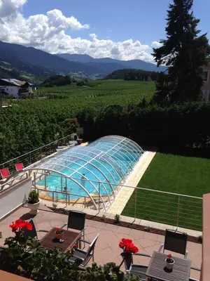 a swimming pool with a glass house in a field at Hotel Ploseblick in Naz-Sciaves