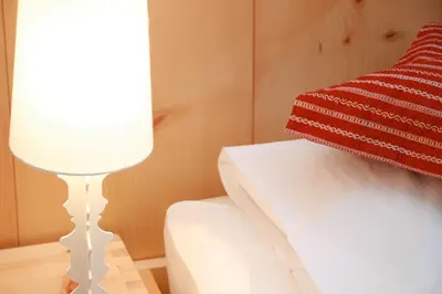 a lamp next to a bed with a red pillow at Hotel Ploseblick in Naz-Sciaves