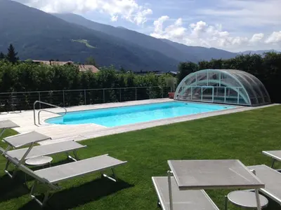 a swimming pool next to a glass house at Hotel Ploseblick in Naz-Sciaves