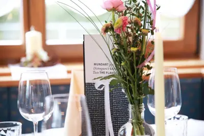 a vase filled with flowers on a table with wine glasses at Hotel Ploseblick in Naz-Sciaves