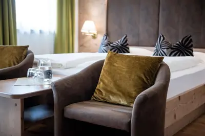 a hotel room with a bed and a chair and a table at Hotel Oberbrunn in Naz-Sciaves