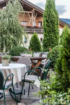 an outdoor patio with tables and chairs and trees at Hotel Oberbrunn in Naz-Sciaves
