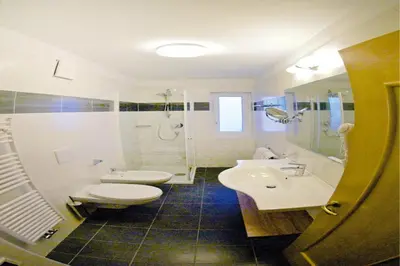 a bathroom with two sinks and a toilet and a shower at Amazing apartment house Diamant with breathtaking view in Santa Cristina in Val Gardena