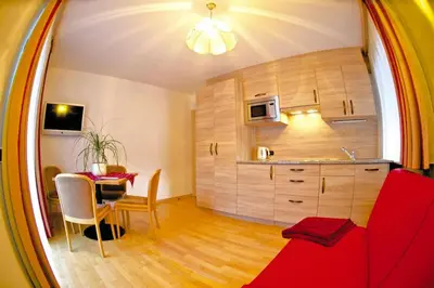a living room with a red couch and a table at Amazing apartment house Diamant with breathtaking view in Santa Cristina in Val Gardena