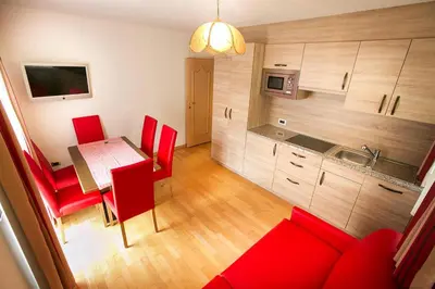 a kitchen and dining room with a table and red chairs at Apartment in Val Gardena near Ski Slopes in Santa Cristina in Val Gardena