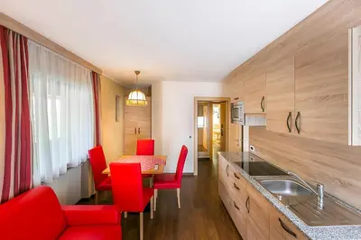 a kitchen with red chairs and a dining table at Apartment in Val Gardena near Ski Slopes in Santa Cristina in Val Gardena