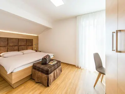 a bedroom with a large bed and a chair at Apartment in Dorf Tirol near tennis court in Tirolo