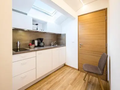 a kitchen with white cabinets and a wooden door at Apartment in Dorf Tirol near tennis court in Tirolo