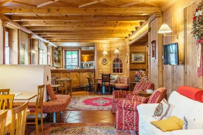 a living room with wooden walls and tables and chairs at Hotel Alemagna in San Vito di Cadore