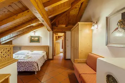 a room with two beds and a couch at Hotel Alemagna in San Vito di Cadore