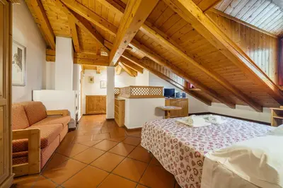 a bedroom with a bed and a couch in a room at Hotel Alemagna in San Vito di Cadore