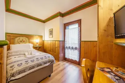 a bedroom with a bed and a large window at Hotel Alemagna in San Vito di Cadore