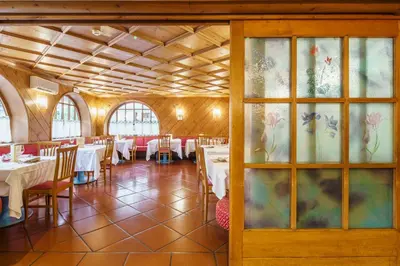 a dining room with tables and chairs and windows at Hotel Alemagna in San Vito di Cadore