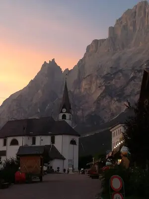 a church with a mountain in the background at Hotel Alemagna in San Vito di Cadore