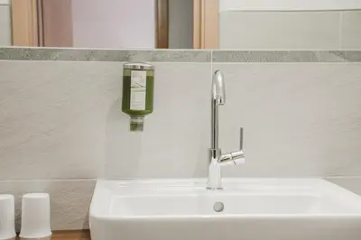 a bathroom sink with a soap dispenser on the wall at Residence Erika - Apartments, Breakfast & Sauna in Siusi