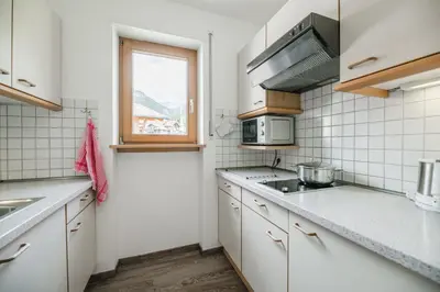 a kitchen with white cabinets and a window at Residence Erika - Apartments, Breakfast & Sauna in Siusi