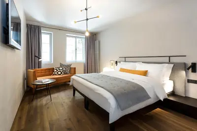 a bedroom with a large bed and a chair at Goldenstern Townhouse in Bolzano