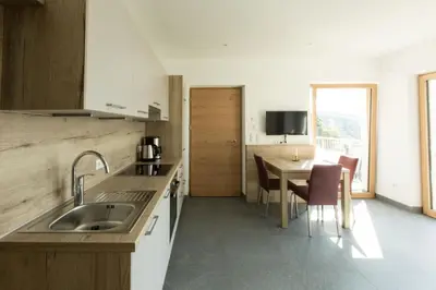 a kitchen with a sink and a table with chairs at Appartements Martinsheim in Tirolo