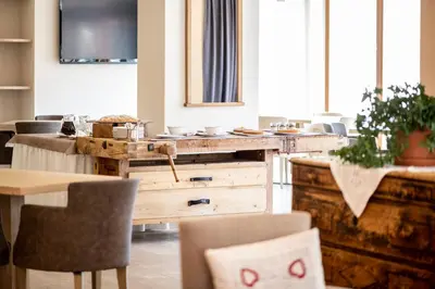 a kitchen with a wooden counter with chairs and a table at Design & Suite Hotel Ciarnadoi in Vigo di Fassa