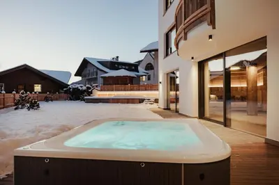 a large wooden barn with a snowy mountain in the background at Luxury Chalet Milé in Ortisei