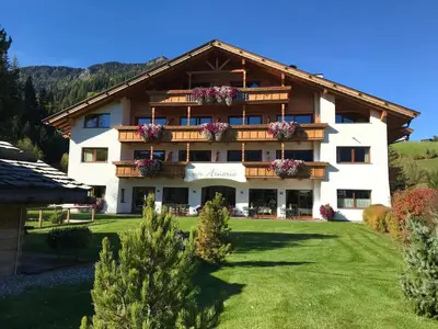 a large white building with flowers on the balconies at Hotel Arnaria in Ortisei