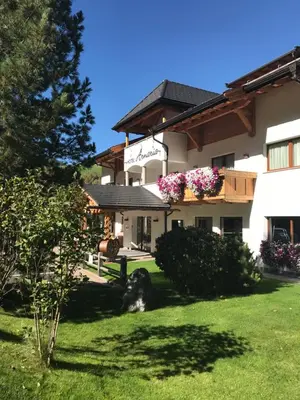 a large white building with flowers in a yard at Hotel Arnaria in Ortisei