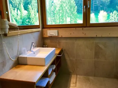 a bathroom with a sink and two windows at Hotel Arnaria in Ortisei
